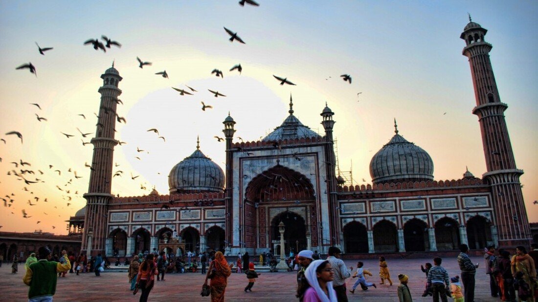 Tour guide explaining Qutub Minar to travellers on a guided sightseeing tour in Delhi